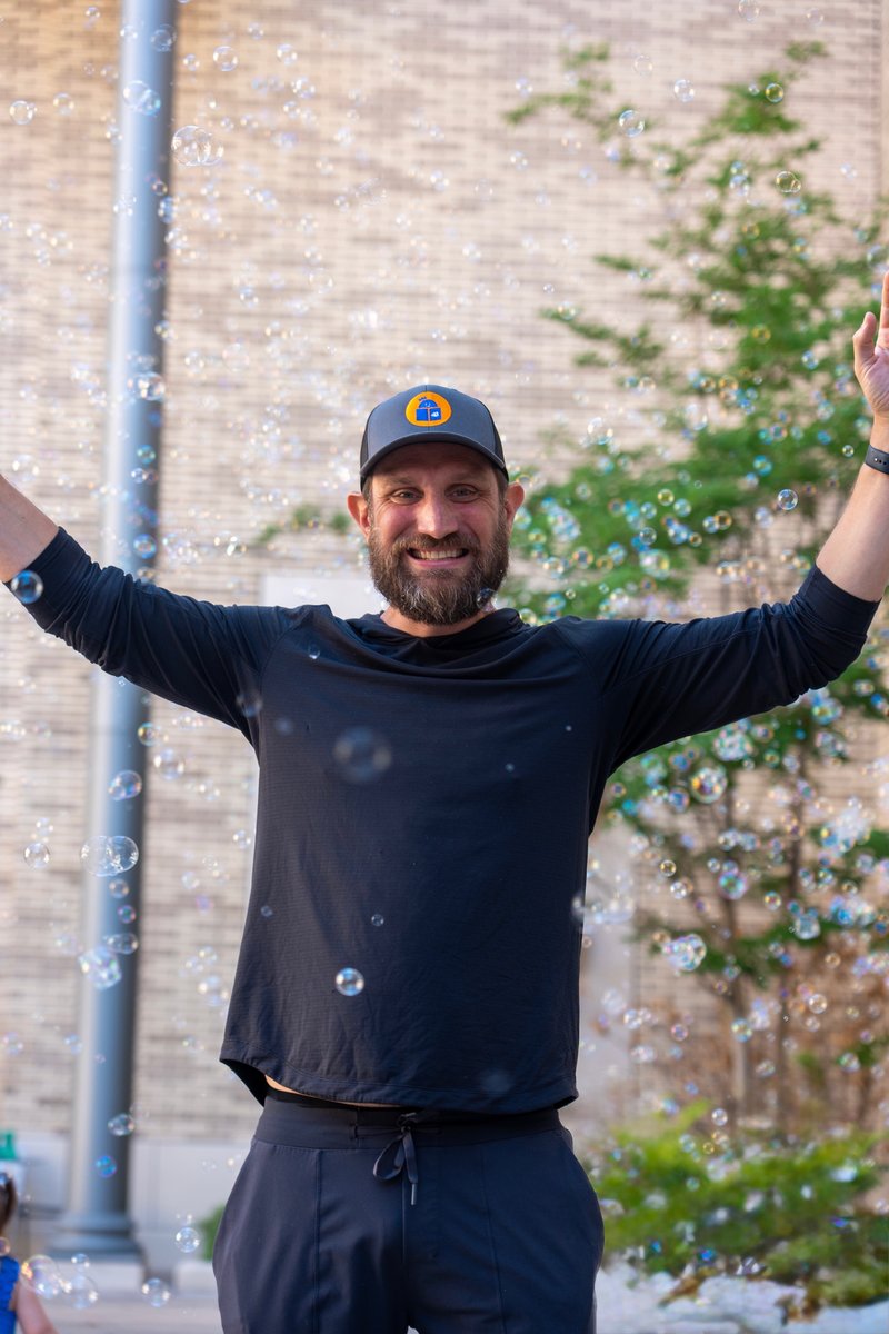 Rich smiling with arms raised, bubbles all around